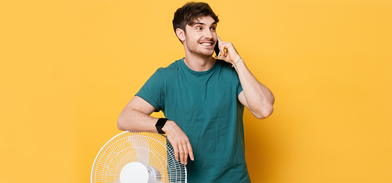 Person on the phone standing next to a room fan.